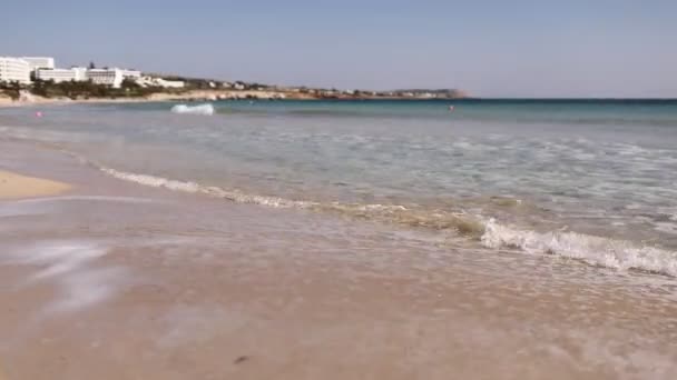 阳光明媚的日子里，大海蓝色的波浪在空旷的海滩上冲破。海浪和美丽的沙滩 — 图库视频影像