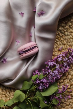 Pembe Fransız kurabiyesi ya da badem kurabiyesi ve kumaş ve saman tezgahında leylak çiçekleri. Doğal meyve ve böğürtlen tatları, kremalı dolma..