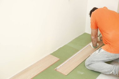 Odaya kaplama ya da parke döşeme, ahşap kaplama döşeme döşemesi, kaplamanın uzunluğunu gösteren işçiler. Kaplamalı döşeme döşemeleri evde. Adam ölçer ve işaretler.