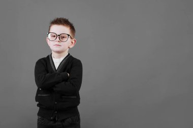 Mavi gömlekli ve mavi arka planda gözlüklü akıllı bir çocuğun portresi, kollarını göğsünün üzerine katladı. Okul eğitimi, bilim ve yenilik kavramı, iş geliştirme