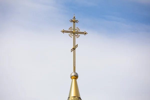 De gouden koepel en het kruis van de orthodoxe kerk tegen de blauwe lucht en wolken. — Stockfoto