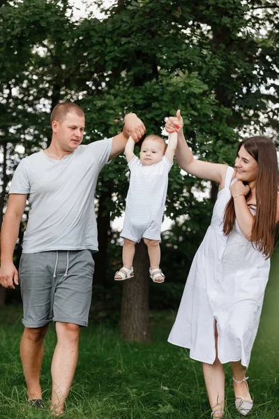 Щаслива молода сім'я, мама, тато і маленький син проводять час разом на відкритому повітрі в літньому зеленому саду — стокове фото