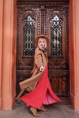 Şehrin sokaklarında poz veren kırmızı elbiseli güzel kız. Şehirde yürüyen çarpıcı genç bir kadın.