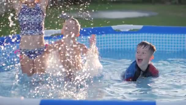 Niños felices nadando en la piscina. amigos chapoteando juguetonamente divirtiéndose nadando juntos en un día soleado disfrutando de agua fría en vacaciones de verano — Vídeos de Stock