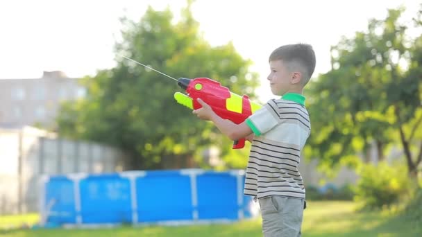 夏天阳光明媚的日子里 小男孩在户外用水枪泼水 暑假的概念 — 图库视频影像
