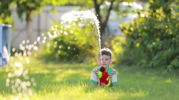 子供の男の子は夏の晴れた日に屋外で水鉄砲で飛び散っています 夏休みのコンセプト — ストック動画