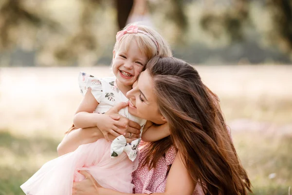 La jeune mère joue avec sa petite fille dans le parc le jour de l'été. Vacances en famille dans le jardin. Portrait maman avec enfant ensemble sur la nature. Maman, petite fille dehors. Bonne fête des mères — Photo