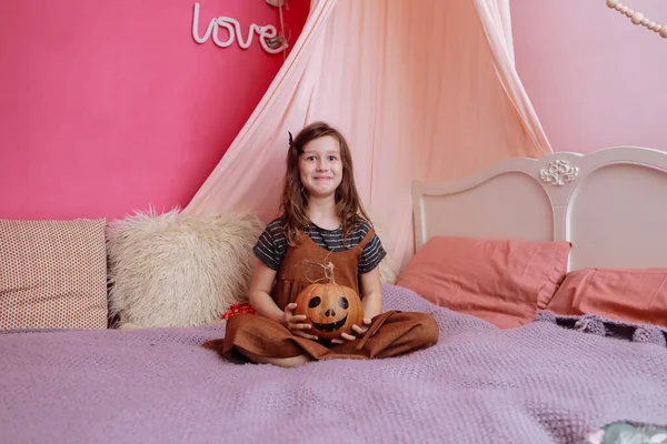 Tatlı Küçük Kız Pembe Odasında Yatağında Cadılar Bayramı Balkabağıyla Oynuyor — Stok fotoğraf