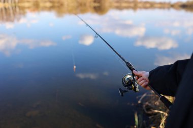 Adam balık yakalar, gölde veya gölde balık tutarken olta çeker. Çubuklu balıkçı, nehir kıyısında dönen makara. Deniz kıyısında, gölde ya da gölette balık avlıyorum. Vahşi doğa, kırsal kaçamak