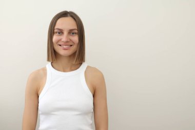 Beyaz atlet bluzlu, düz omuzlu, kahverengi saçlı, beyaz arka planda izole edilmiş kameraya bakan 30 'lu yaşlardaki beyaz Avrupalı çekici kadının portresi. Halk yaşam tarzı konsepti.