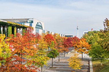 Berlin, Almanya - 20 Ekim 2020: Paul Loebe Allee sonbahar renkli ağaçlar, Alman Federal Başbakanlık binası (Bundeskanzleramt) ve televizyon kulesi ile kaplıydı. 