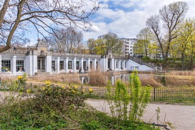 Berlin, Almanya - 25 Nisan 2021: Ördek havuzlu bahçe anıtı Rudolph Wilde Park ve yer üstü metro istasyonu Rathaus Schoeneberg ile Carl-Zuckmayer köprüsü