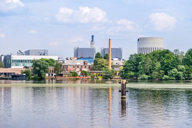 Berlin, Almanya - 28 Haziran 2021: Vattenfall Europe Waerme tarafından işletilen Reuter West kojenerasyon fabrikasıyla birlikte Haselhorst ilçesinin kıyısındaki Havel Nehri üzerindeki Frieda-Arnheim-Promenade manzarası