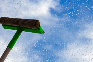 Mavi gökyüzüne karşı köpüklü bir fırçayla pencereyi yıkamak, yakın plan. Saflık ve tazelik kavramı.