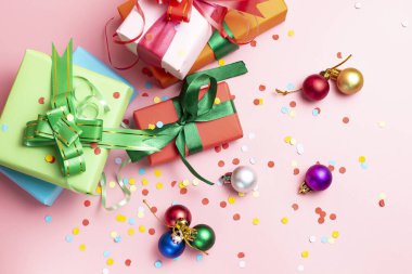 Kutulardaki hediyeler tatil paketlerinde ve pembe bir arka planda Noel topları. Noel konsepti. Düz konum, üst görünüm, kopyalama alanı. 