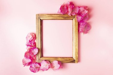 Pembe arka planda begonvil tomurcuklarıyla çevrili koyu ahşap çerçeve. Boşluğu kopyala, üst görünüm, düz uzanma.