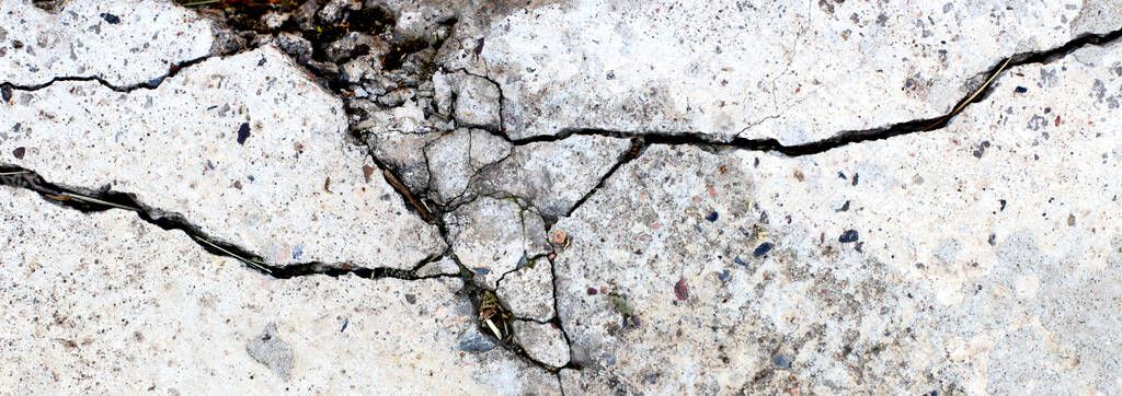 Concrete surface with large cracks as a background or backdrop, wide banner.
