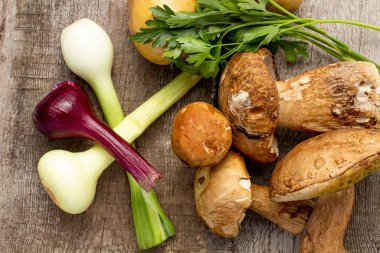 Basit bir yemek için bir takım ürünler, Porcini mantarlı patates veya Boletus edulis ve rustik arka planda soğan..