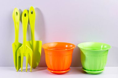 Renkli saksılar ve bir takım küçük bahçe aletleri, gri arkaplan, kopyalama alanı.