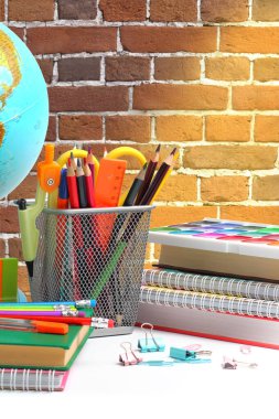 Okul malzemeleri masada, tuğla duvar da fon olarak. Okula dönmek ya da eğitim kavramı.