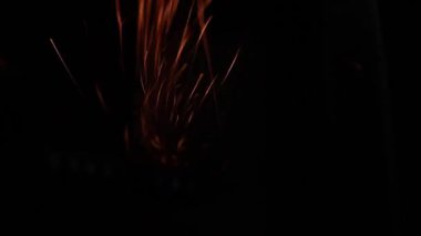 Değirmen taşından yükselen parlak metal kıvılcımları, kıvılcımlar, koyu arkaplan, yakın plan.