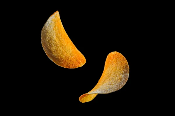 Падіння картопляних чіпсів ізольовано на чорному тлі — стокове фото