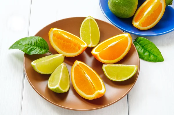 Orange segments with leaves on white wooden surface — Stock Photo, Image