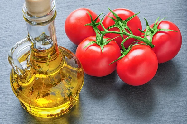 Botella de aceite de oliva con hierbas y tomates rojos — Foto de Stock