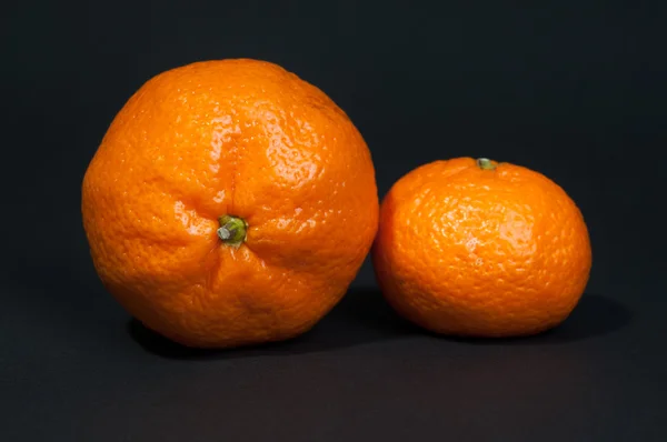 Two big and small tangerine on black background — Stock Photo, Image