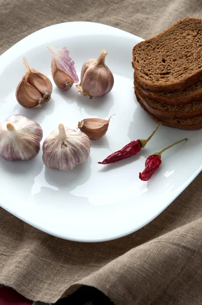 Close up still life of bread, garlic and pepper on linen cloth — Stock Photo, Image