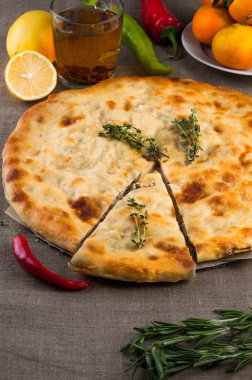 Calzone pizza veya tavuk mantar pasta biber, limon, biberiye ve çay ile üstten görünüm keten kumaş arka plan üzerinde