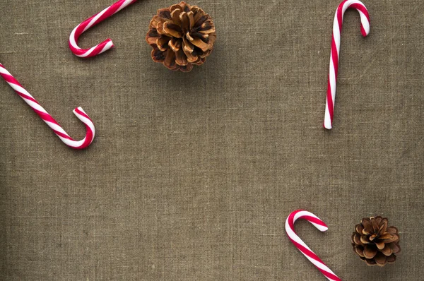 Weihnachtsdekoration: Draufsicht auf Zuckerstangen und Zapfen auf Leinenstoff-Hintergrund mit freiem Platz — Stockfoto