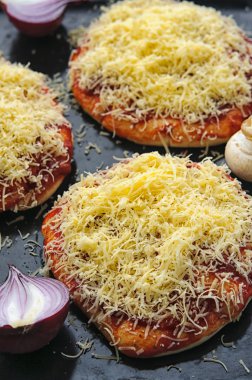 Mini pizza veya siyah bakışta yüzey yakın çekim makro üzerinde peynir kaplı küçük granül