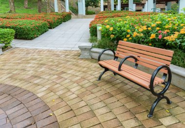 Kamu parkında renkli çiçek arkaplanı olan boş bir koltuk 