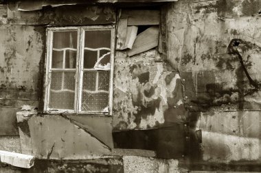 Terk edilmiş evin duvarında kırık bir pencere.