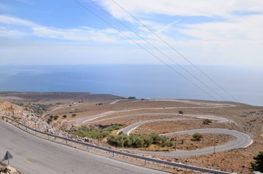 Dağ yolu. Avrupa 'nın deniz kıyısındaki dağlarda dolambaçlı bir yol. Güzel beyaz bulutlu mavi gökyüzü. Güzel dağ manzarası.