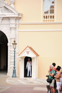 Monako Prensi 'nin konutunda görevli beyaz üniformalı onur muhafızı. Prince 's Palace' ın önündeki meydan, güneşli bir gün, bir sürü turist..
