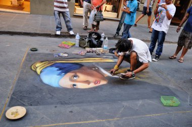 Floransa, İtalya - 19 Ağustos 2011: Bir sokak ressamı, Floransa sokaklarında asfalt üzerinde renkli boya kalemleriyle inci küpeli bir kız resmi çiziyor.