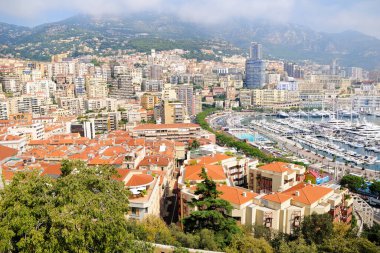 Monako 'daki Monte Carlo limanının panoramik manzarası. Herkül Limanı. Limanda yatlar. Hava manzarası, şehir manzarası. Ön plandaki evlerin çatıları..