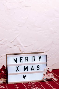 Beyaz beton ve kırmızı yılbaşı desenli arka planda küçük ışık kutusu. Tahta Noel oyuncakları.