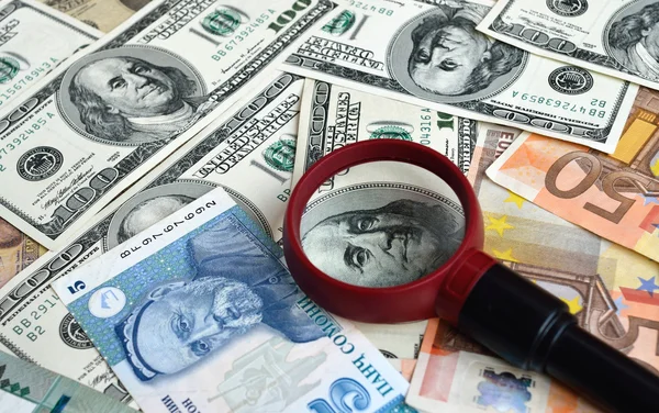 Strewn banknotes with a magnifier — Stock Photo, Image