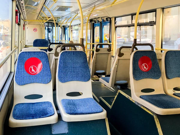 Interior of empty public city bus with information signs on seats about the observance of social distance