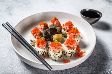 Suşi rulosunu avokado, ton balığı, somon ve havyarla hazırla. Gri arka plan. Üst görünüm.