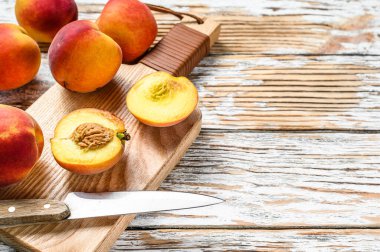 Taze şeftali, doğrama tahtasında organik meyve. Beyaz ahşap arka plan. Üst Manzara. Boşluğu kopyala