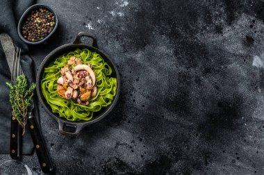 Peynirli, deniz mahsullü, karides, mürekkep balığı, ahtapot ve midyeli yeşil ıspanaklı fettucine makarna. Karanlık arka plan. Üst Manzara. Boşluğu kopyala.