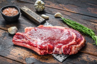 Çiğ kovboy ya da et satırının kemiğinde pirzola. Mermer biftekli pirzola. Koyu ahşap arka plan. Üst görünüm.