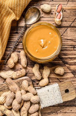 Ahşap masada kavanozda kremalı fıstık ezmesi, organik yemek. Ahşap arka plan. Üst görünüm.