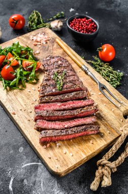 Kesme tahtasında baharatlı ızgara biftek. Mangal bifteği. Siyah arka plan. Üst görünüm
