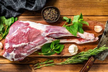 Biber ve sarımsaklı keçi bacağı. Çiğ çiftlik eti. Ahşap arka plan. Üst görünüm.