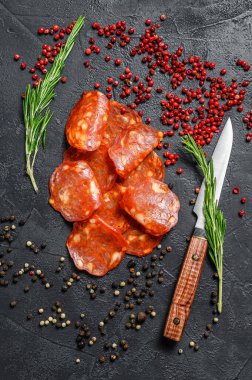 Chorizo sosisi ince kesilmiş. Baharatlı İspanyol salamı, kırmızı biber, biber. Baharatlı yemek. Siyah arka plan. Üst görünüm.